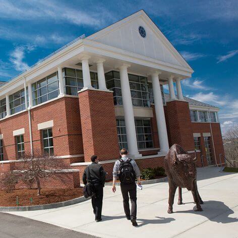 two students walking by a statue of a bison