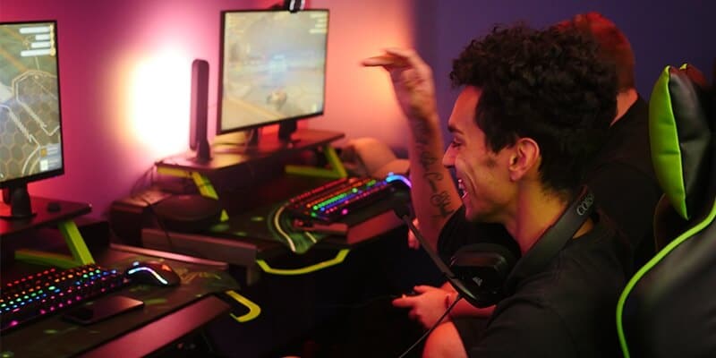 Side view of two students playing video games in Nichols College's eSports room