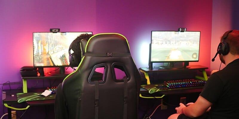 Back view of two students playing video games in Nichols College's eSports room