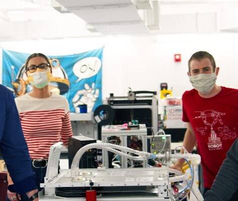 Nick Anderson and three other persons standing next to a ventilator