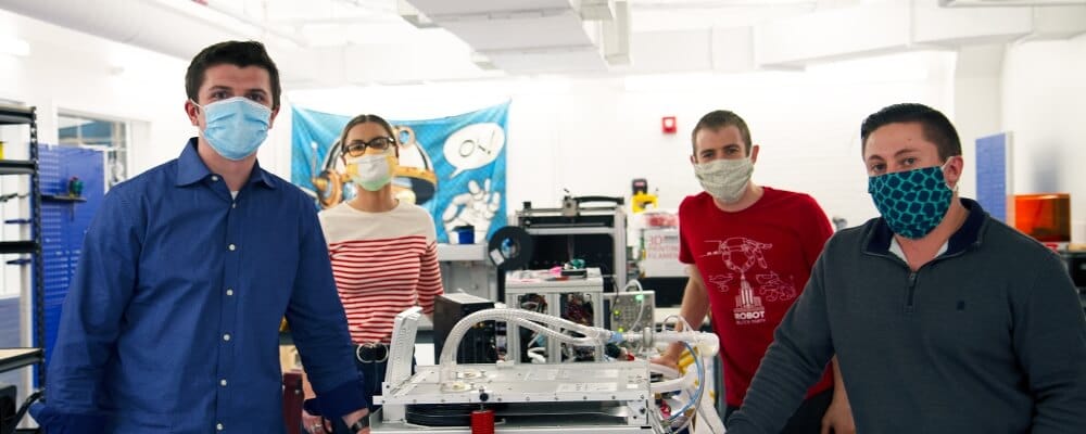 Nick Anderson and three other persons standing next to a ventilator