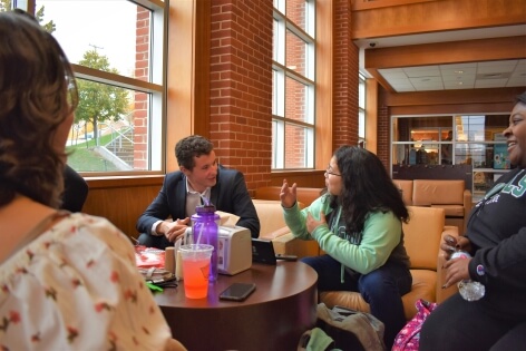 Spencer Molloy sitting with and talking to fellow students