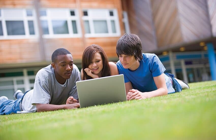 Students using laptop on lawn
