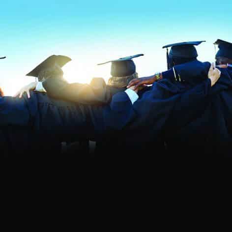 Graduates with arms around shoulders looking at the sunset