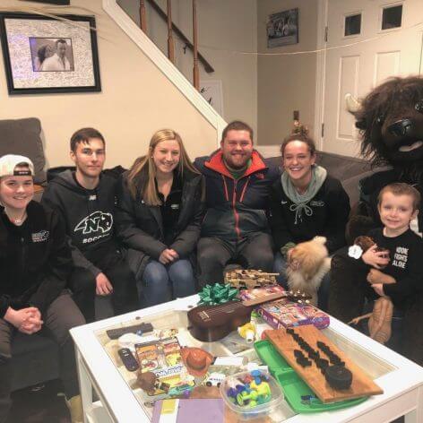 Nichols students sitting on a couch with Quinn Waters and Nichols College's bison mascot, Thunder.