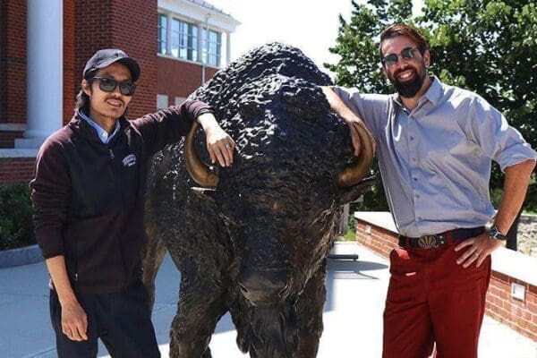 Charles Tousignant and David Leary standing next to a bison statue.