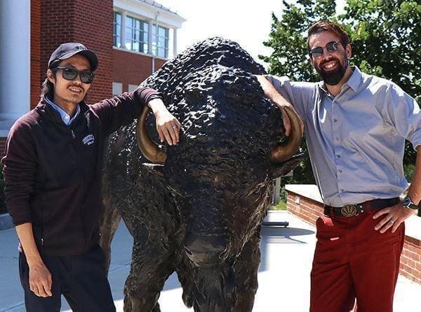 Charles Tousignant and David Leary standing next to a bison statue.