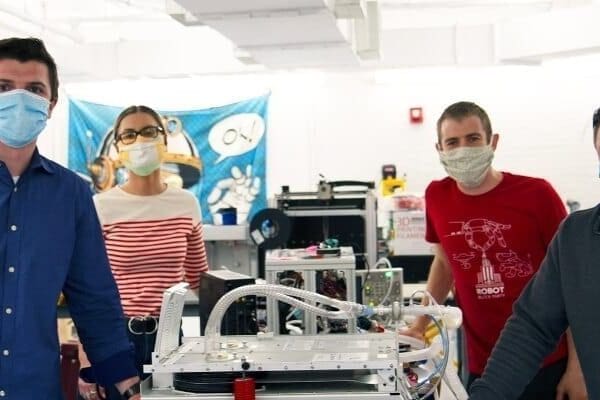 Nick Anderson and three other persons standing next to a ventilator