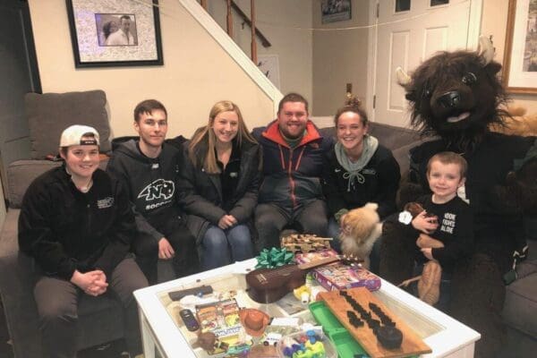 Nichols students sitting on a couch with Quinn Waters and Nichols College's bison mascot, Thunder.