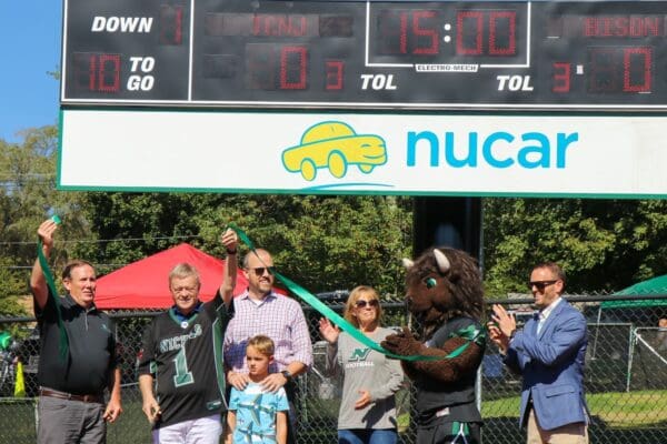 Members of the Dagesse family with President Sulmasy, cutting the ribbon for the new video scoreboard on Vendetti Field at Nichols College.
