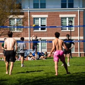 Nichols College students play a game of volleyball on the campus green on a sunny spring afternoon.