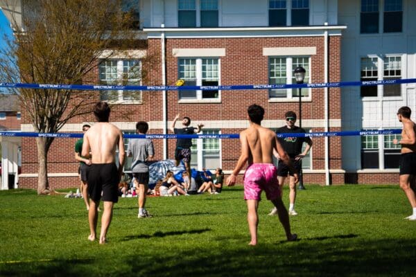 Nichols College students play a game of volleyball on the campus green on a sunny spring afternoon.