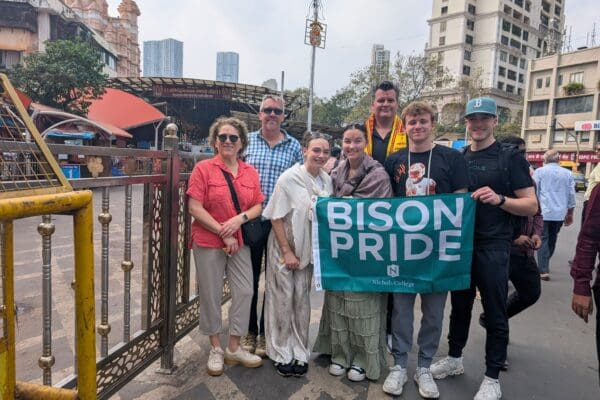 Nichols College students and faculty hold a Bison Pride banner outside a temple during a study abroad trip.