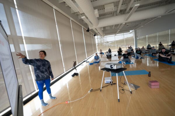 A group of students learn yoga in the fitness studio inside the Athletic Center.