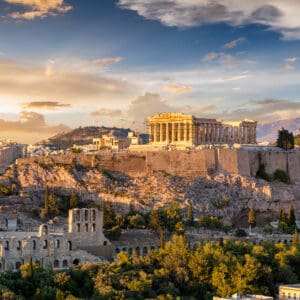 Panoramic sunset view of the Acropolis and Parthenon atop a rocky hill overlooking the city of Athens, Greece